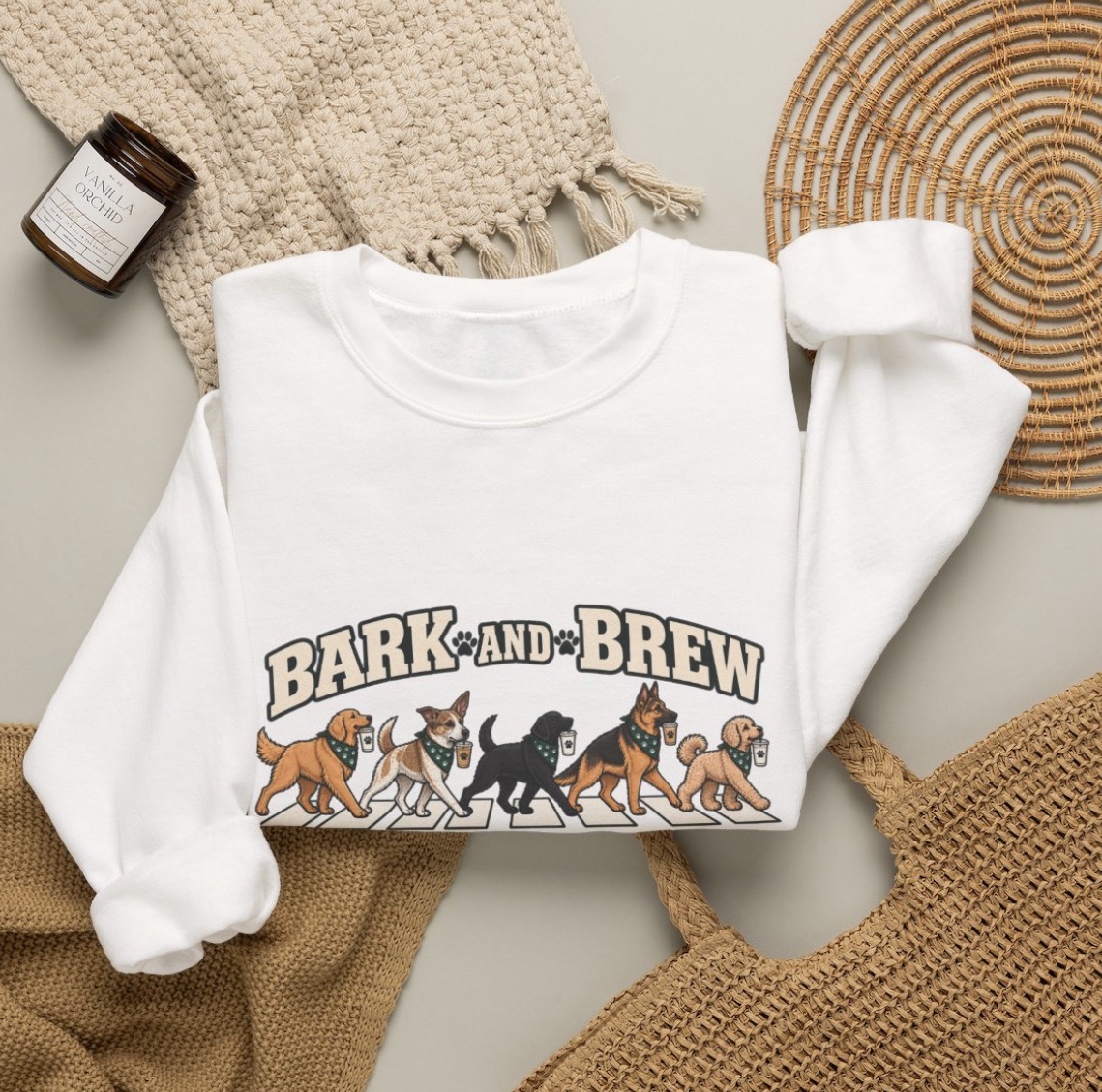 White sweatshirt printed with five bandana-wearing dogs carrying coffee cups under the Bark & Brew wordmark